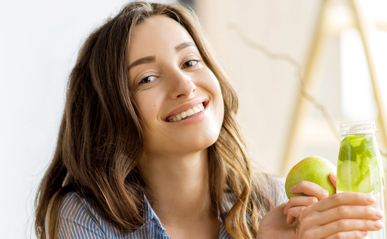 Beautiful happy woman sitting with drinks and healthy green food at home. Vegan meal and detox concept Beautiful happy woman sitting with drinks and healthy green food at home. Vegan meal and detox concept
