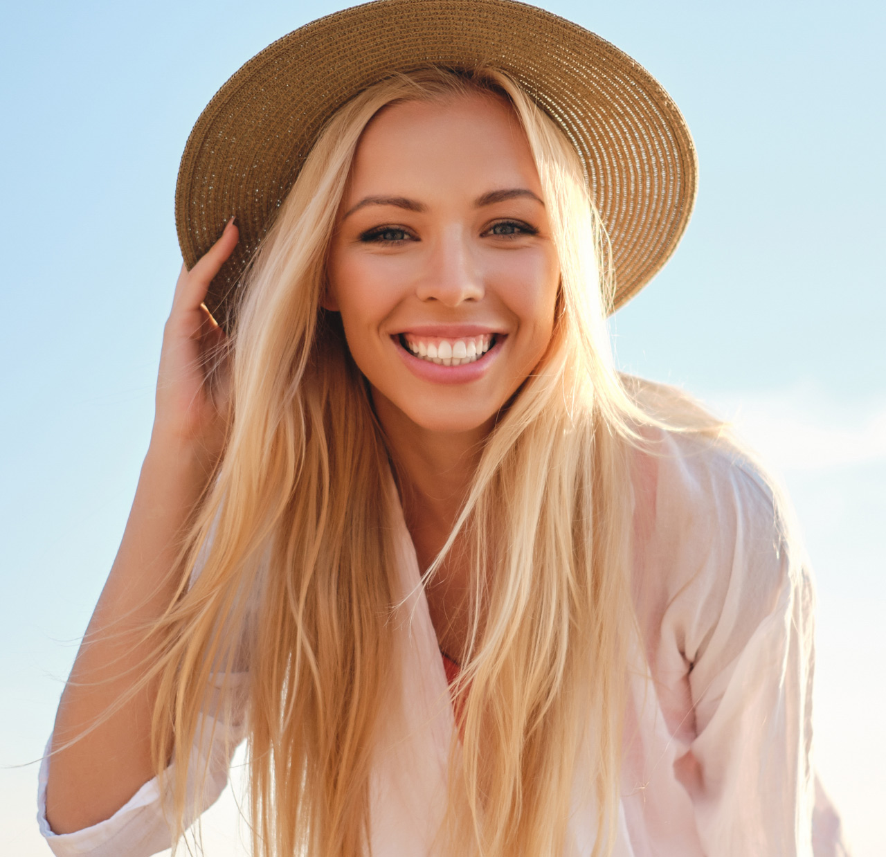 Young attractive smiling blond woman in shirt and hat joyfully looking in camera with sea on background Young attractive smiling blond woman in shirt and hat joyfully looking in camera with sea on background