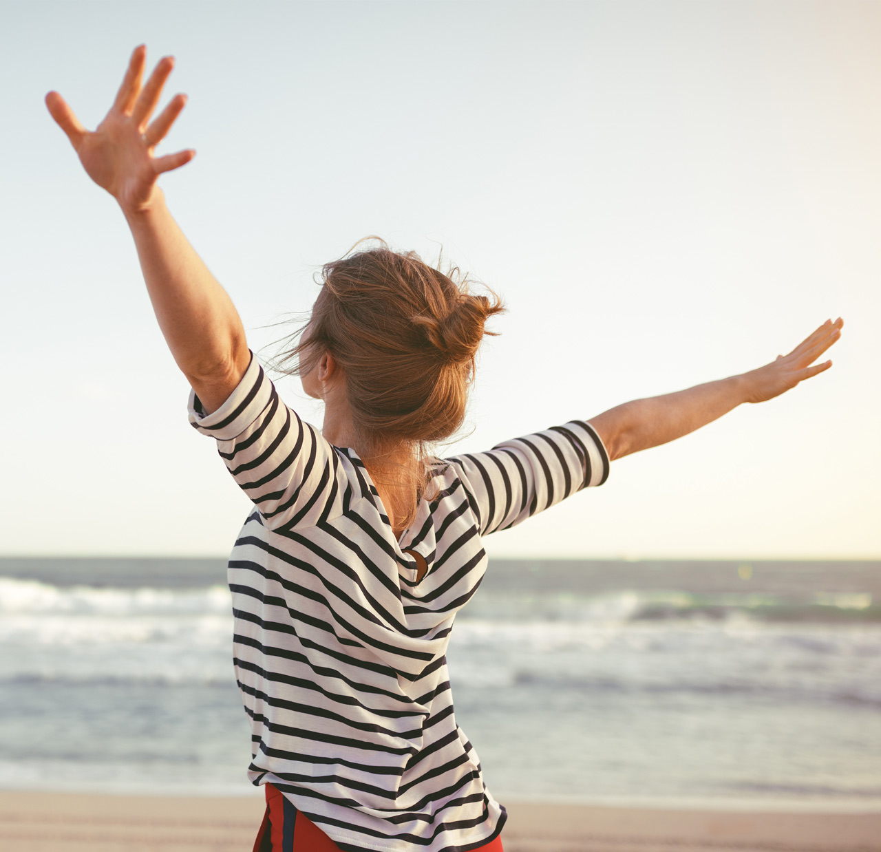 happy woman enjoying freedom with open hands on sea