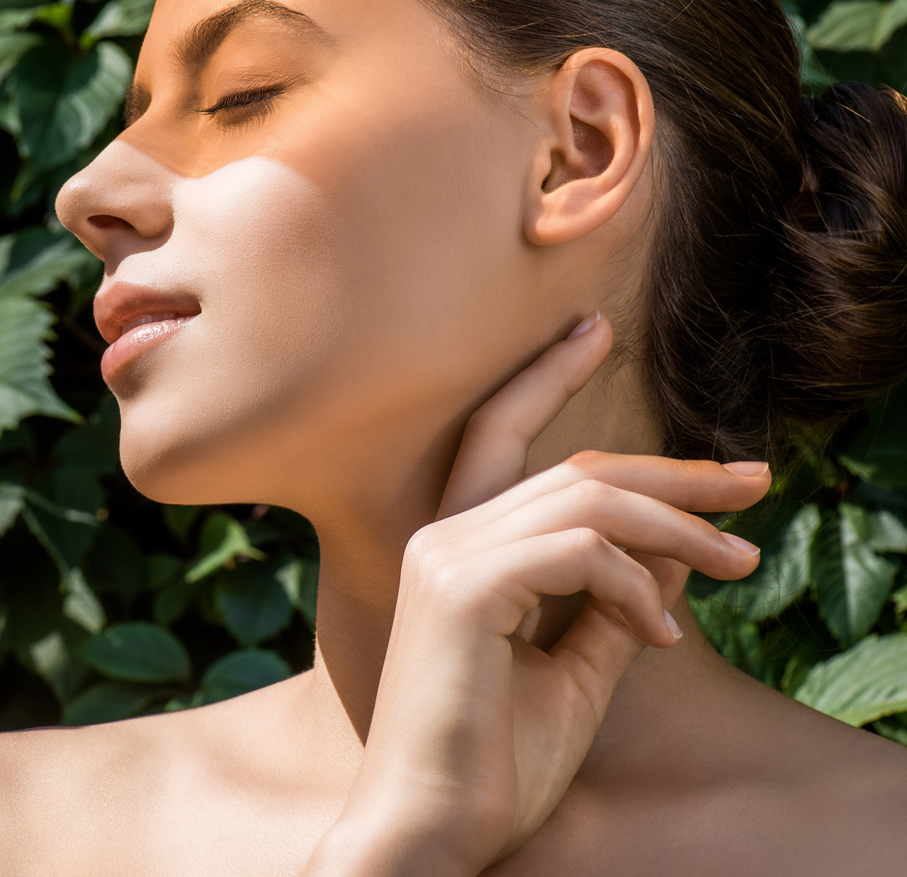young woman with orange shadow on face and leaves at background young woman with orange shadow on face and leaves at background